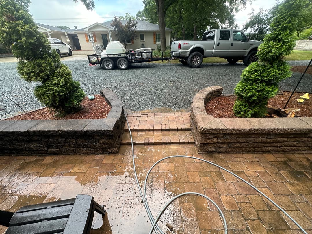 Driveway with gravel, a parked truck and trailer, and landscaped brick pathway.