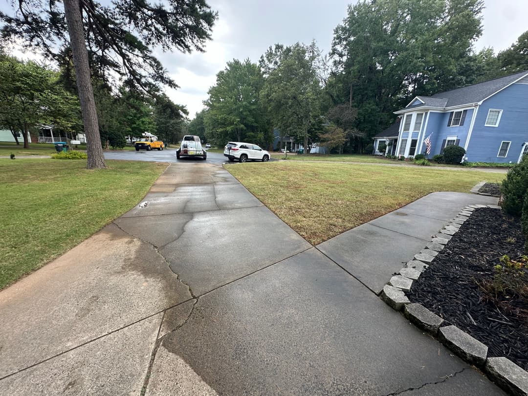 Driveway view with parked cars, lush green lawn, and home in a residential neighborhood.